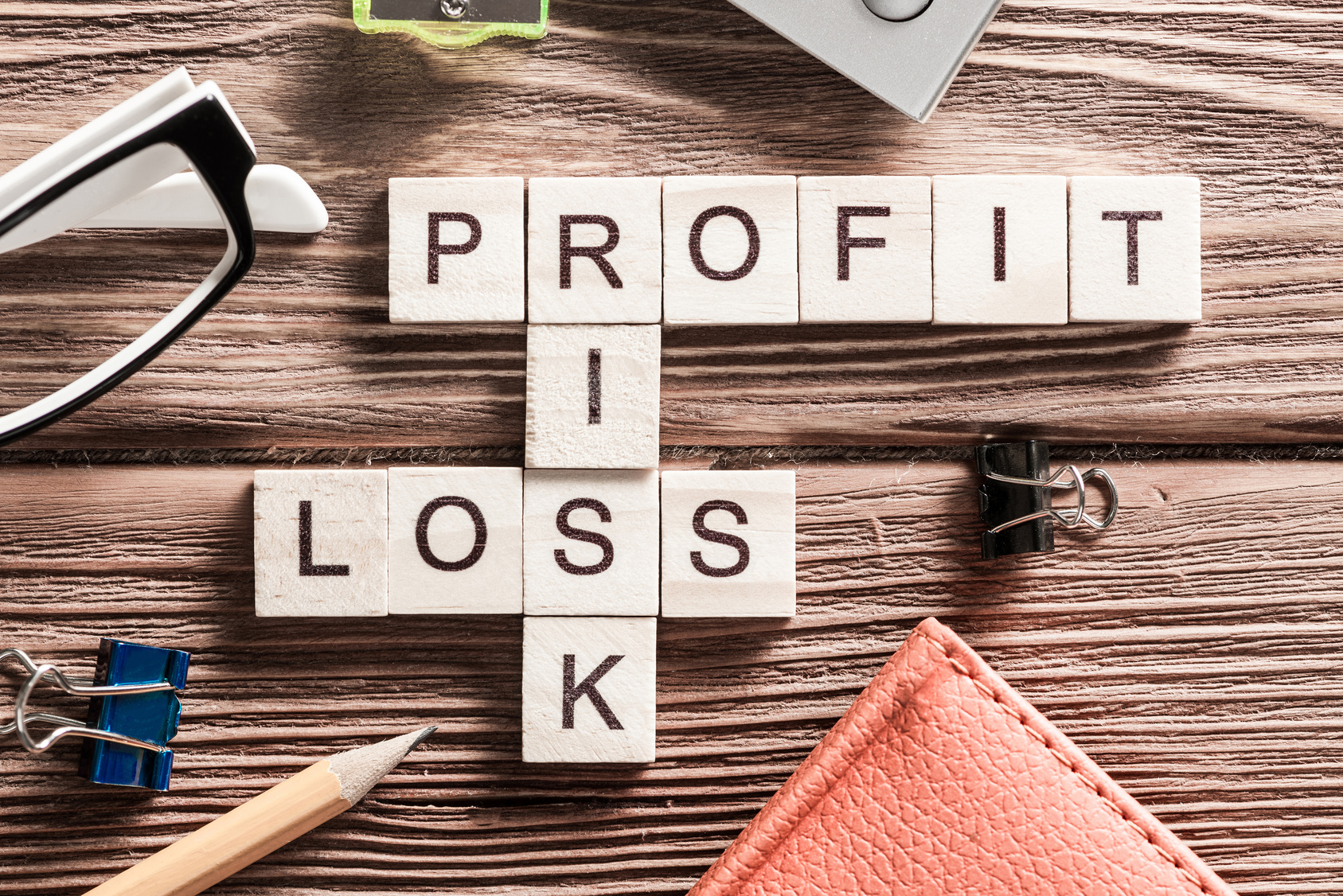 Profit, loss, and risk in letter tiles on cluttered desk